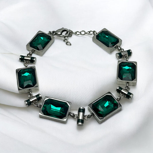 Armband med smaragdgröna glasstenar och metallinfattning